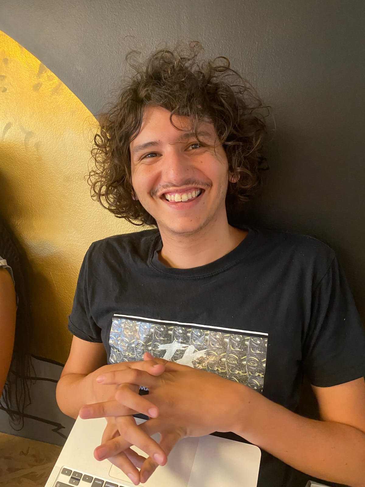 Homme souriant devant un fond noir et or